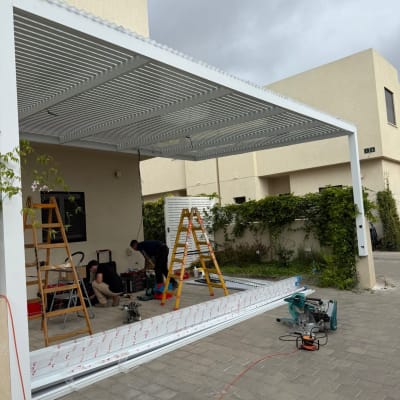 התקנת פרגולה אלומיניום בחצר עם סולמות וכלים