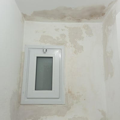 קיר עם סימני רטיבות ליד חלון קטן