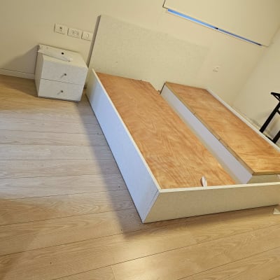 מיטה מפורקת וחלקי ריהוט על רצפת עץ