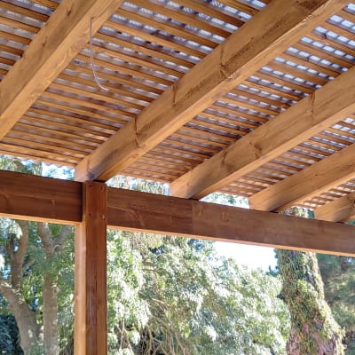 פרגולה מעץ עם קורות עץ חומות בגינה