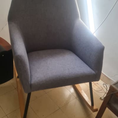 כיסא אפור עם כרית ומשענת, נעלי בית על הרצפה