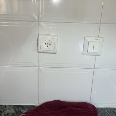 שקע חשמל ומתג על קיר אריחים לבן