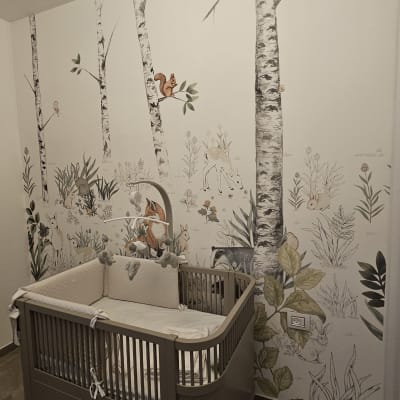 קיר מעוצב עם טפט יער ועריסה בחדר ילדים