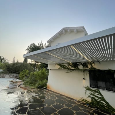 פרגולה מאלומיניום ליד בית עם גינה