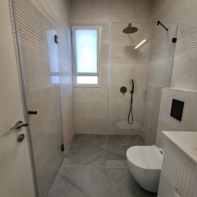 חדר אמבטיה עם מקלחון ושירותים מודרניים