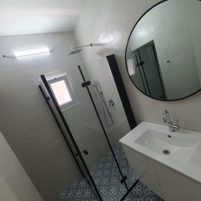 חדר אמבטיה עם מקלחון, כיור ומראה עגולה