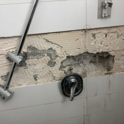 ברז מקלחת על קיר עם אריחים שבורים