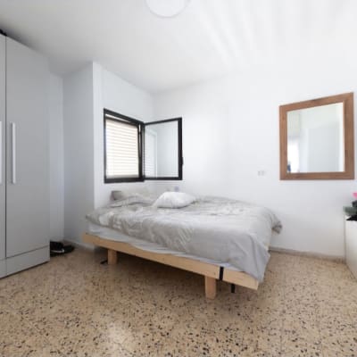 חדר שינה עם מיטה, ארון ומראה על הקיר