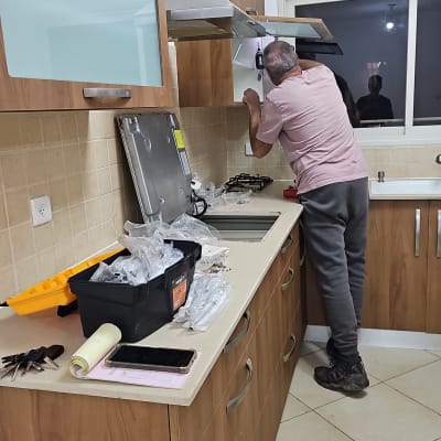 נגר מתקין ארון מטבח עם כלים על השיש