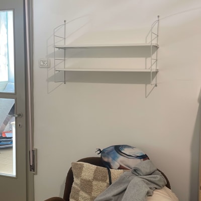 מדף תלוי על הקיר מעל כורסה עם בגדים