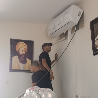 שני אנשים מתקינים מזגן על קיר