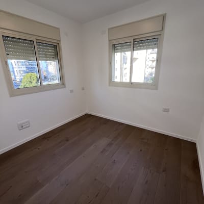 חדר ריק עם רצפת עץ נקייה ושתי חלונות