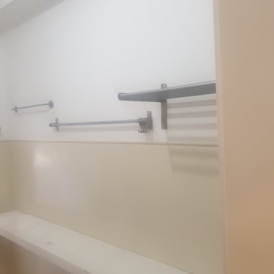 קיר צבוע בלבן עם מדפים ומוטות מתכת