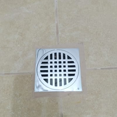 פתח ניקוז מתכת מרובע על רצפת קרמיקה