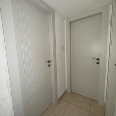 שתי דלתות לבנות במסדרון עם רצפת אריחים