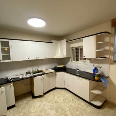 מטבח עם ארונות לבנים ומשטח עבודה כהה