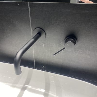 ברז וכפתור שחור על קיר אריחים כהה