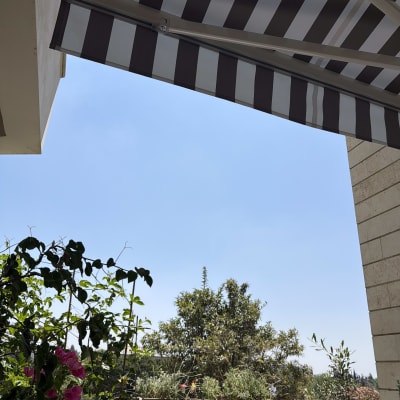 סוכך זרועות מותקן מעל מרפסת עם צמחים