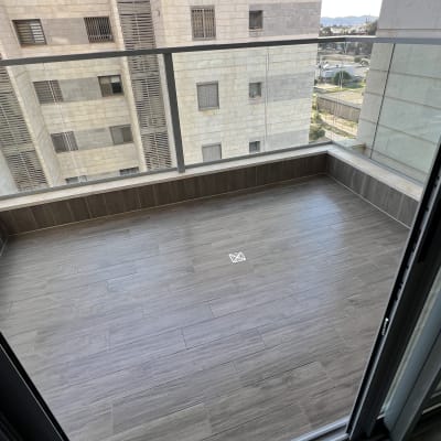 מרפסת נקייה עם רצפת אריחים ומעקה זכוכית