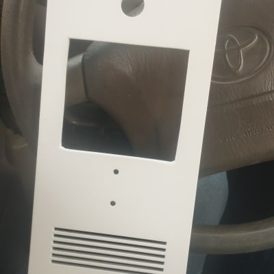 מסגרת לבנה עם חורים ומגרעות על רקע הגה רכב