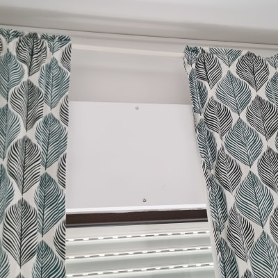 וילונות תלויים על מוט מעל חלון עם תריסים