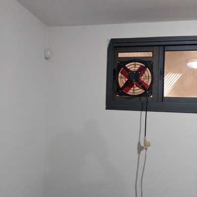מאוורר מותקן בחלון אלומיניום עם חוט חשמל תלוי