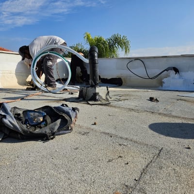 אדם עובד על איטום גג עם צינור וכלים