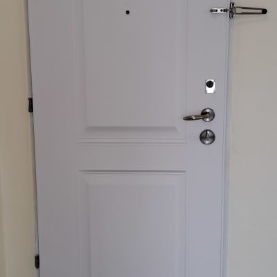 דלת לבנה עם ידית מתכת ובריח בטיחות