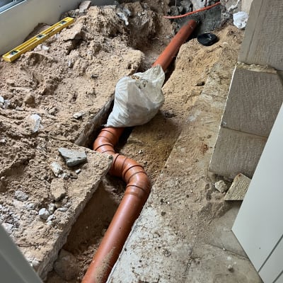 צינור כתום מונח בתעלה עם אדמה וחול