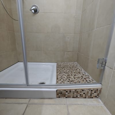 מקלחון עם דלת זכוכית, רצפת פסיפס וברז מתכת