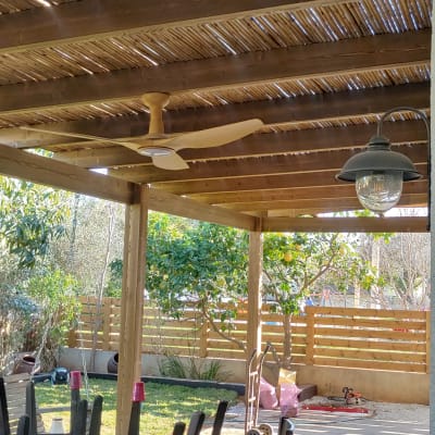 פרגולה מעץ עם מאוורר תקרה וגינה ברקע