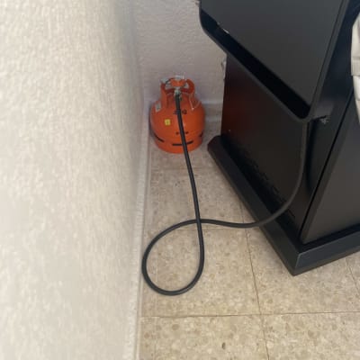 בלון גז כתום מחובר לצינור ליד מכשיר שחור