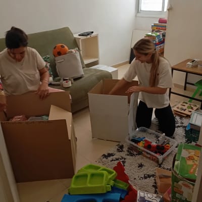 שתי נשים אורזות קופסאות בחדר עם צעצועים