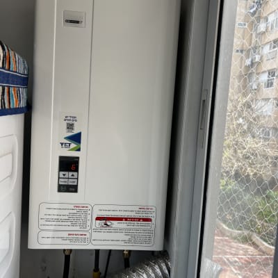 דוד גז מותקן ליד חלון עם צינור פליטה