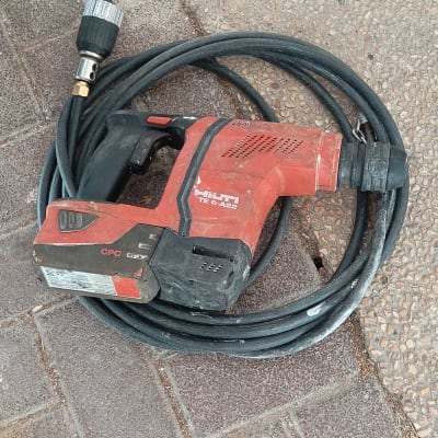 מקדחה אדומה עם כבל שחור על רצפה