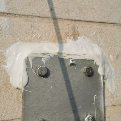 לוח מתכת עם ברגים ומריחה של חומר לבן