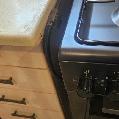 כיריים גז עם כפתורי שליטה וצינור גז מחובר