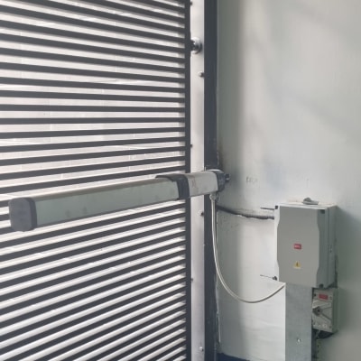 שער חשמלי עם מנגנון פתיחה וסגירה על קיר