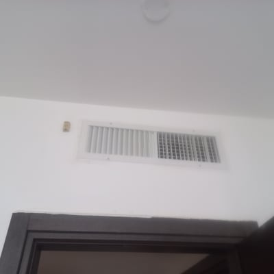 פתח אוורור על קיר לבן מעל דלת