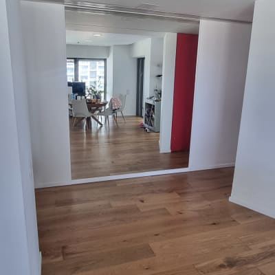 מראה גדולה על קיר בחדר עם רצפת עץ