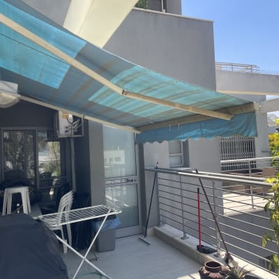 מרפסת עם סוכך כחול, כיסאות ושולחן מתקפל