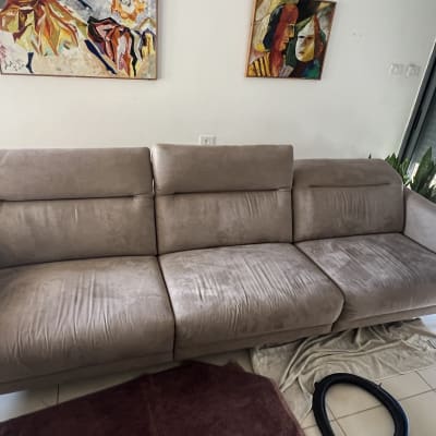 ספה עם כתמים, צינור שואב אבק ומגבת על הרצפה