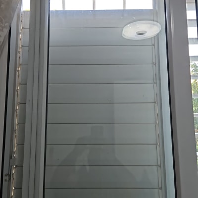 תריסים מותקנים על חלון זכוכית עם וילון בצד