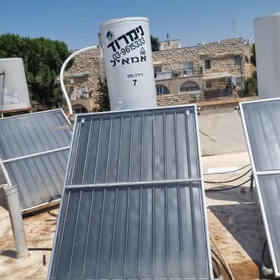 דוד שמש עם קולטים על גג תחת שמיים כחולים