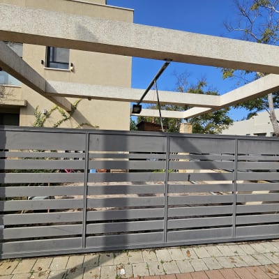 שער חשמלי מתכת אפור עם קורות אופקיות