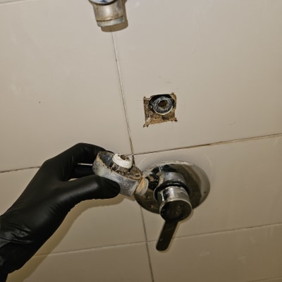 יד עם כפפה מחזיקה חלק ברז חלוד