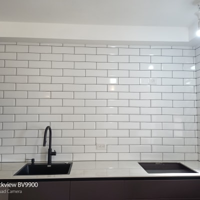 קיר אריחים לבנים עם כיור וברז שחור