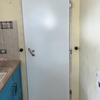 דלת לבנה מותקנת במטבח עם ארונות כחולים