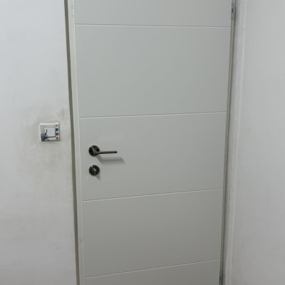 דלת לבנה עם ידית מתכת על קיר לבן