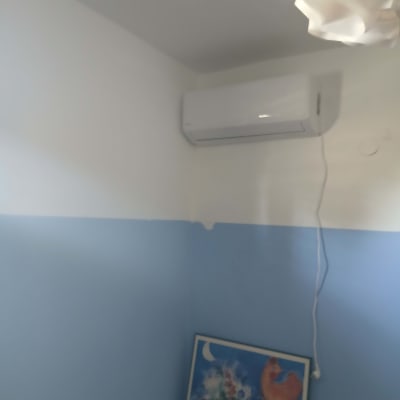 מזגן מותקן על קיר לבן עם כבל חשמל